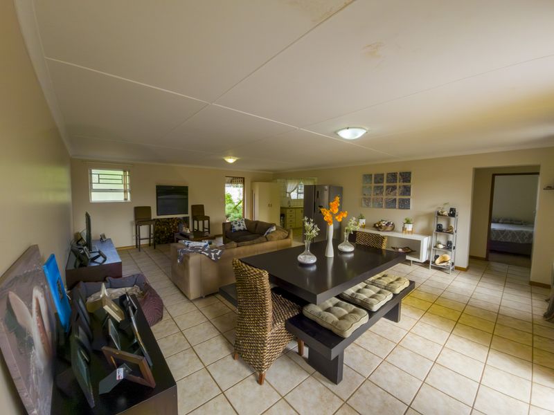 Spacious open-plan living and dining area featuring tiled flooring and direct access to the kitchen, with visible ceiling water staining.