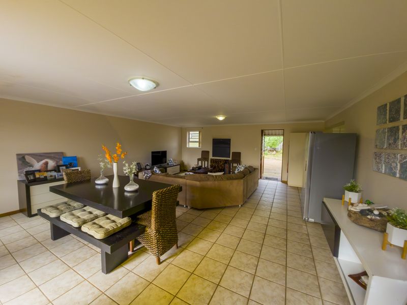 Spacious open-plan living and dining area featuring neutral wall tones, tiled flooring, and direct access to the exterior.