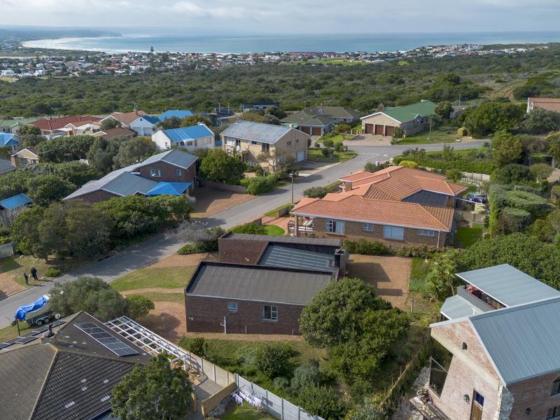 An aerial view of the residential property and surrounding coastal neighborhood, showcasing the roof structure, driveway, and local landscape.