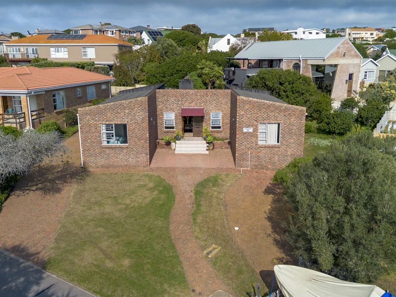 Aerial view of a single-story brick house featuring a paved front walkway, established lawn, and a covered entrance.