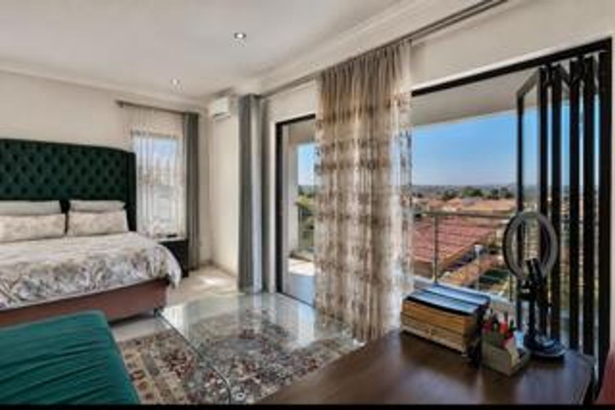 Spacious bedroom featuring recessed lighting, air conditioning, and large bi-fold doors opening to a balcony with expansive neighborhood views.