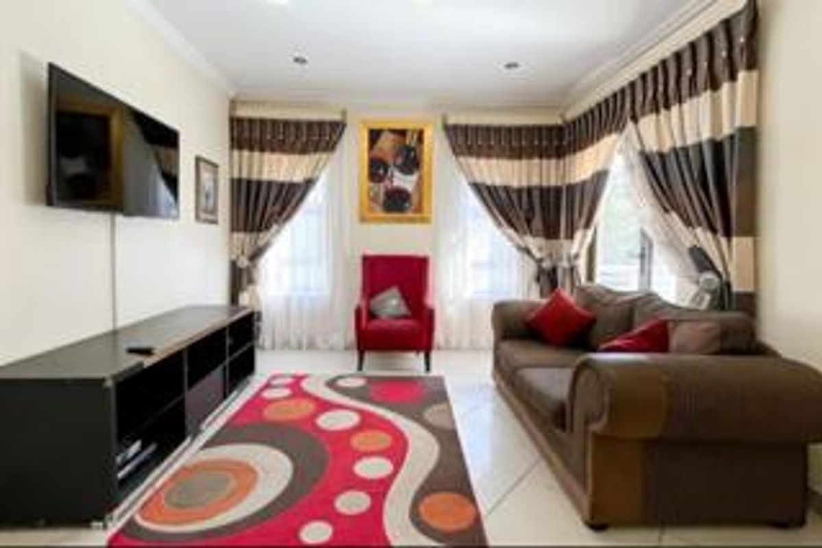 A comfortable living room featuring tiled flooring, recessed downlighting, and decorative cornicing, providing a functional space for relaxation.