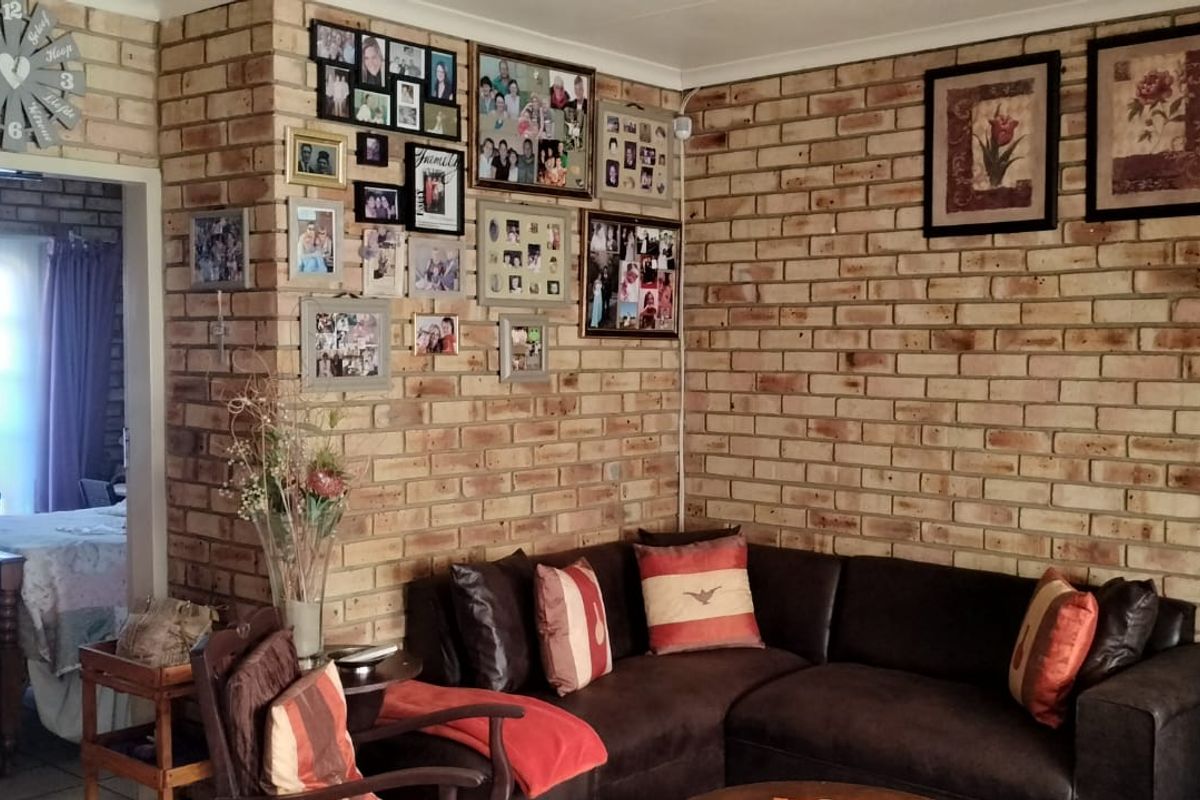 A cozy living room featuring rustic exposed brick walls and an open transition into an adjacent bedroom space.