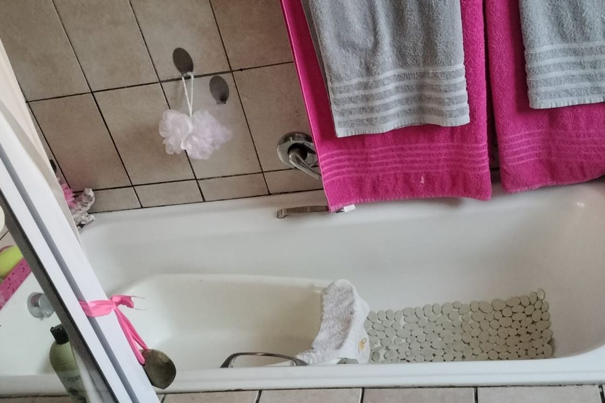 A standard bathroom featuring a built-in bathtub with wall tiling and chrome fixtures.