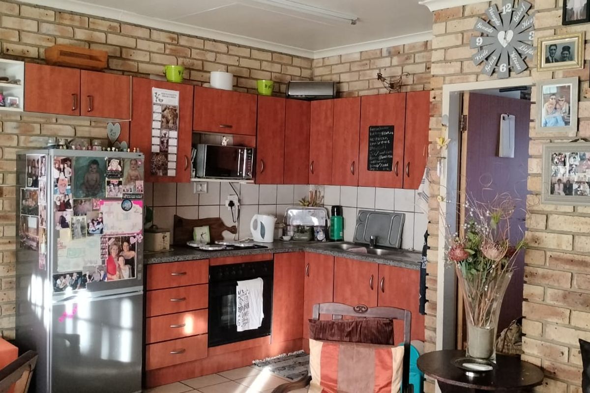A functional kitchen featuring exposed brick walls, wood-tone cabinetry, built-in oven, and tiled backsplash, offering a rustic aesthetic with potential for modern updates.