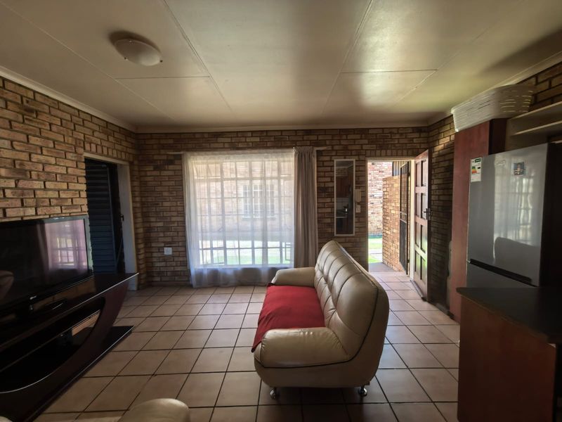 Open plan living area featuring exposed brick walls, tiled flooring, and direct access to the exterior through a security door.