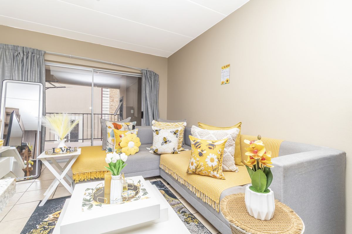 A bright living room featuring tiled flooring and a large sliding glass door providing access to an outdoor balcony area.