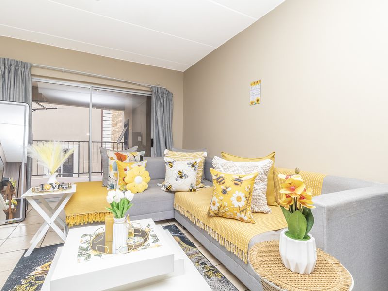 A bright living room featuring tiled flooring and a large sliding glass door providing access to an outdoor balcony area.