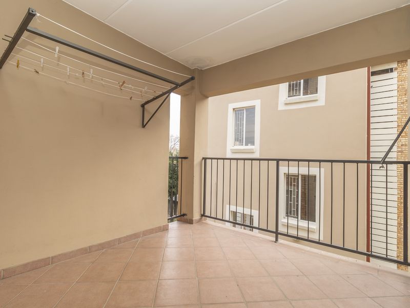 A covered balcony featuring tiled flooring, a metal safety balustrade, and a built-in braai area, providing a functional outdoor space.
