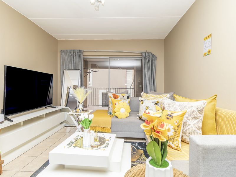 A bright living room featuring tiled flooring and a large sliding glass door that provides access to an outdoor balcony area.