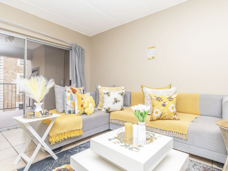 A bright living room featuring tiled flooring and a large sliding glass door providing access to an outdoor balcony area.