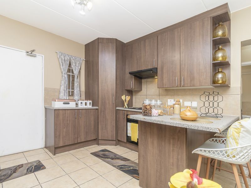 A functional kitchen featuring wood-look laminate cabinetry, granite countertops, built-in oven, extractor fan, and neutral ceramic floor tiling.