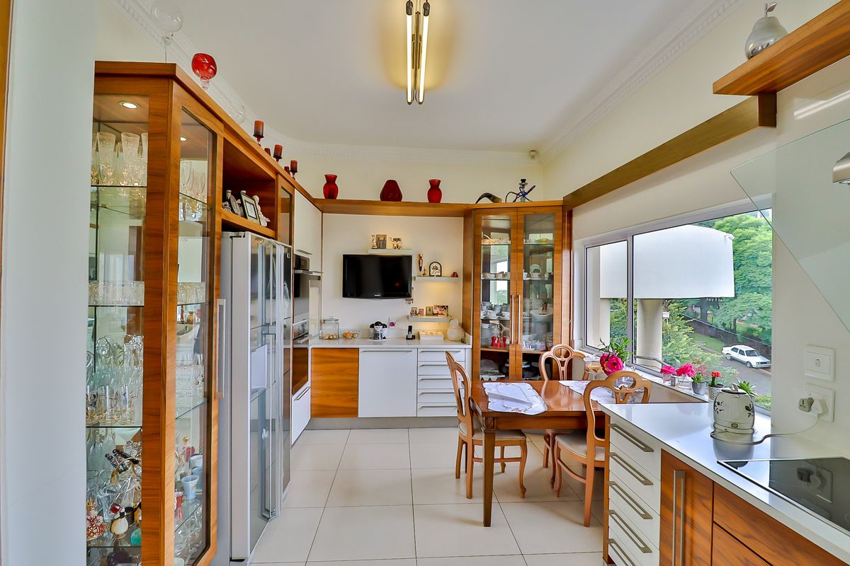 A well-maintained kitchen featuring extensive built-in wooden cabinetry, glass display units, ceramic tile flooring, and a large window providing natural light.