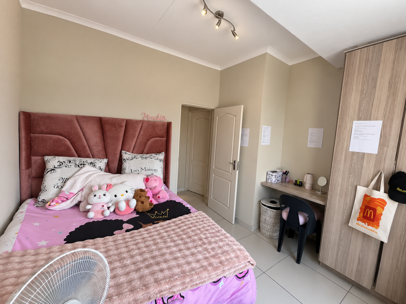 A well-maintained bedroom featuring neutral walls, tiled flooring, a built-in wardrobe, and a functional built-in desk area.