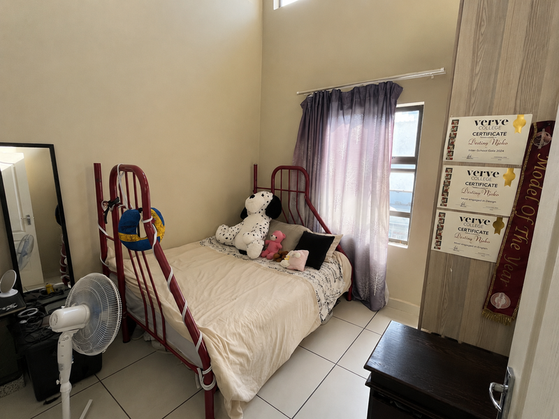 A compact bedroom featuring tiled flooring and a built-in cupboard, offering a functional space with natural light from the window.