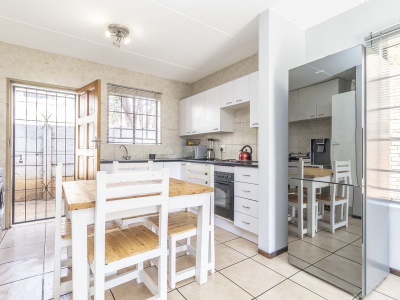 Functional kitchen featuring white cabinetry, tiled backsplash, built-in oven and hob, with direct access to an outdoor area through a security gate.