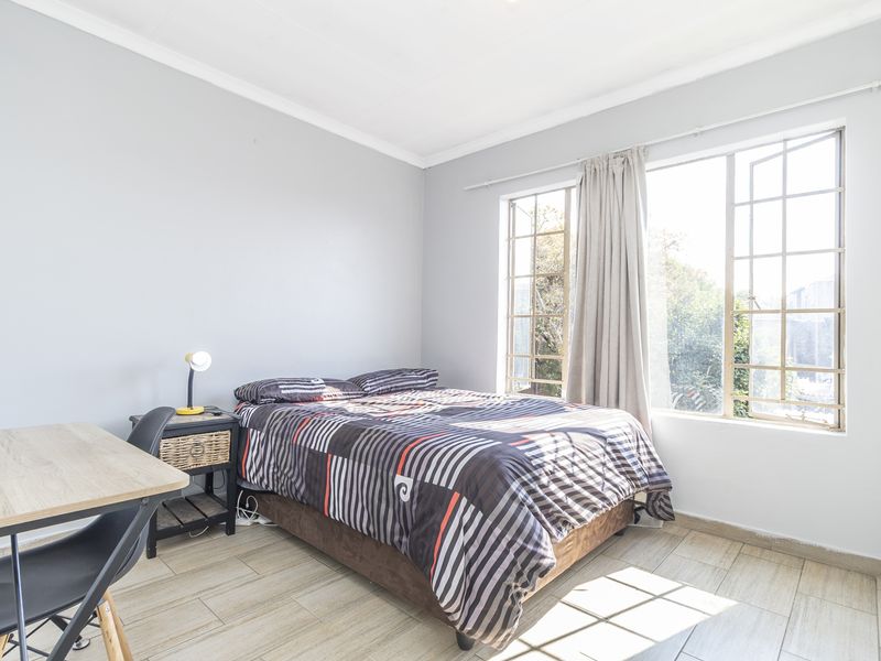 A bright bedroom featuring tiled flooring and large windows that provide ample natural light.