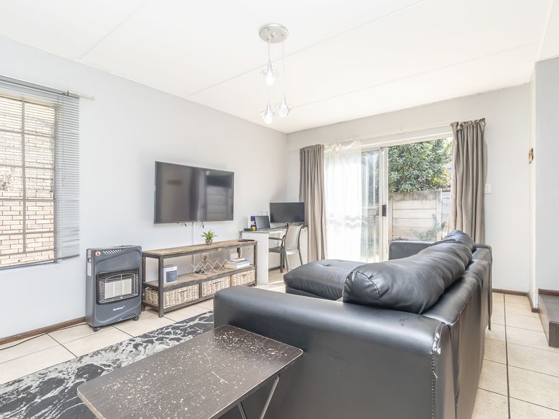 Bright living room featuring tiled flooring, pendant lighting, and a sliding glass door providing access to the outdoor area.