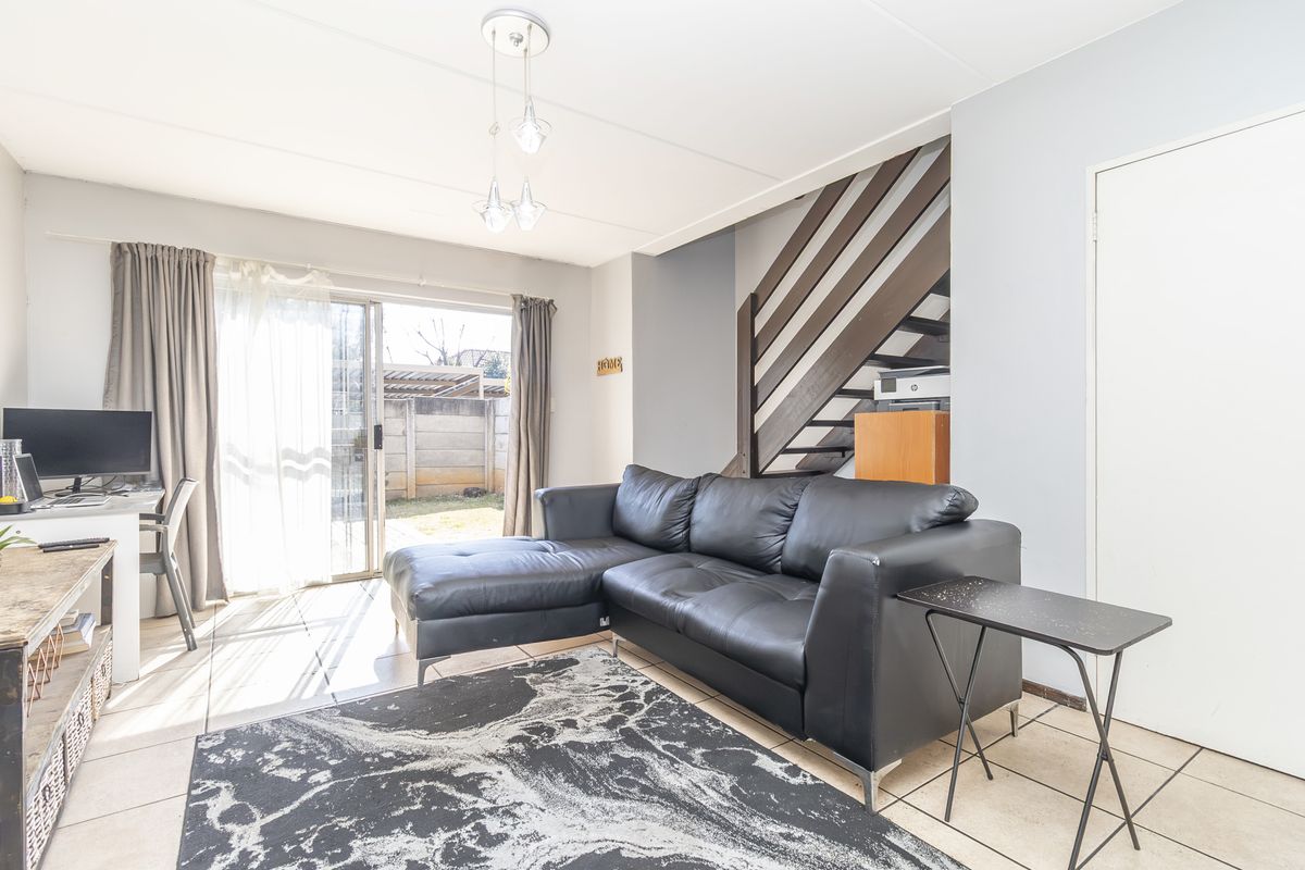 Open-plan living area featuring tiled flooring, a staircase with a timber balustrade, and a sliding glass door providing access to the rear garden.