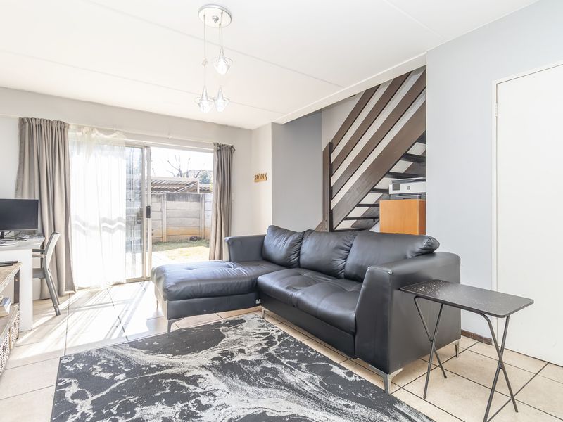 Open-plan living area featuring tiled flooring, a staircase with a timber balustrade, and a sliding glass door providing access to the rear garden.