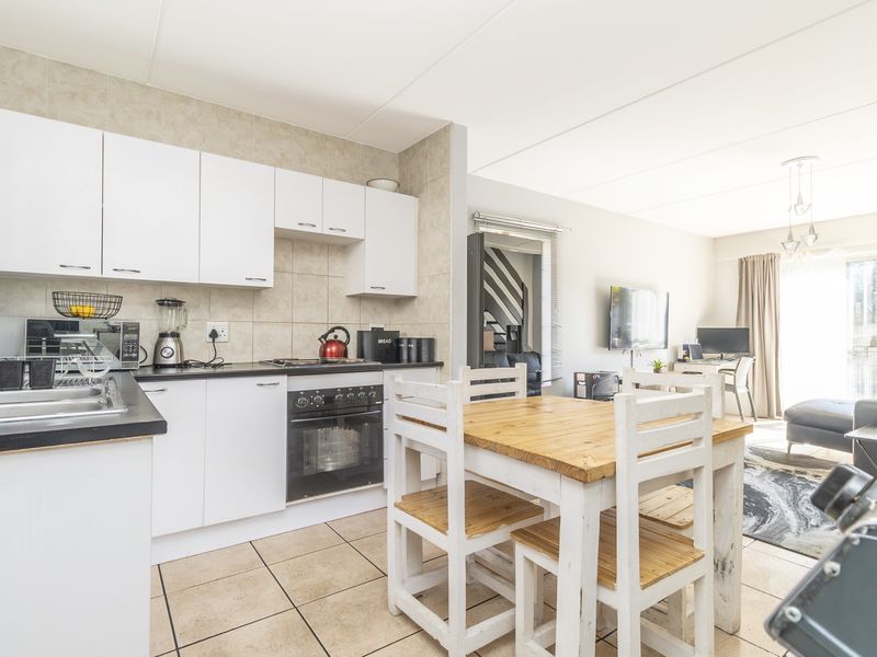 Open-plan kitchen and living area featuring white cabinetry, tiled flooring, and direct access to an outdoor space through sliding glass doors.