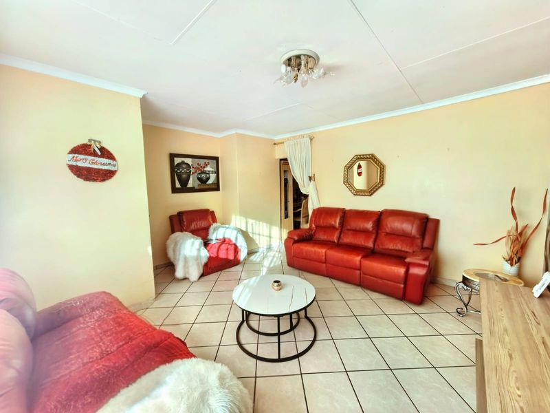 A living room featuring tiled flooring, coving, and a central ceiling light fixture with a dated ceiling tile finish.