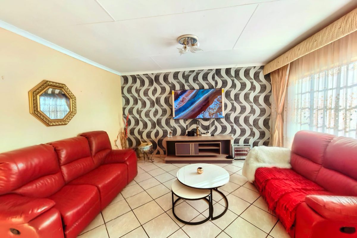 A well-lit living room featuring tiled flooring, a decorative patterned feature wall, and neutral wall finishes, providing a comfortable and functional living space.