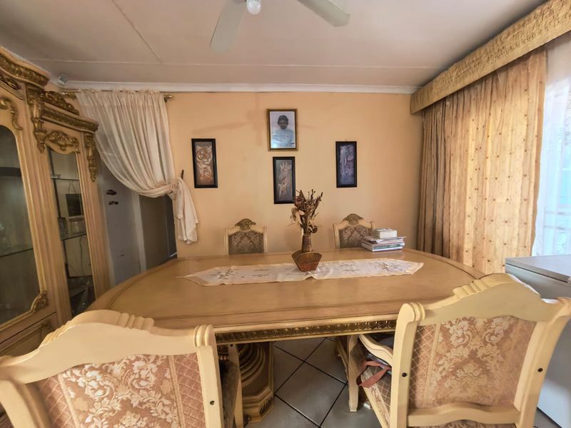 A dining room featuring tiled flooring and a ceiling fan, with neutral wall tones and window treatments.