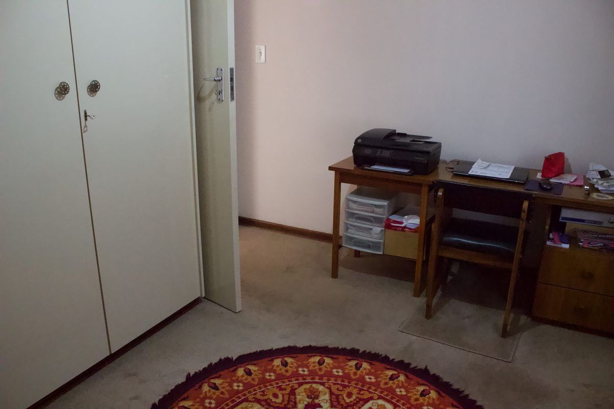 A bedroom featuring a built-in wardrobe and carpeted flooring, currently utilized as a home office space.
