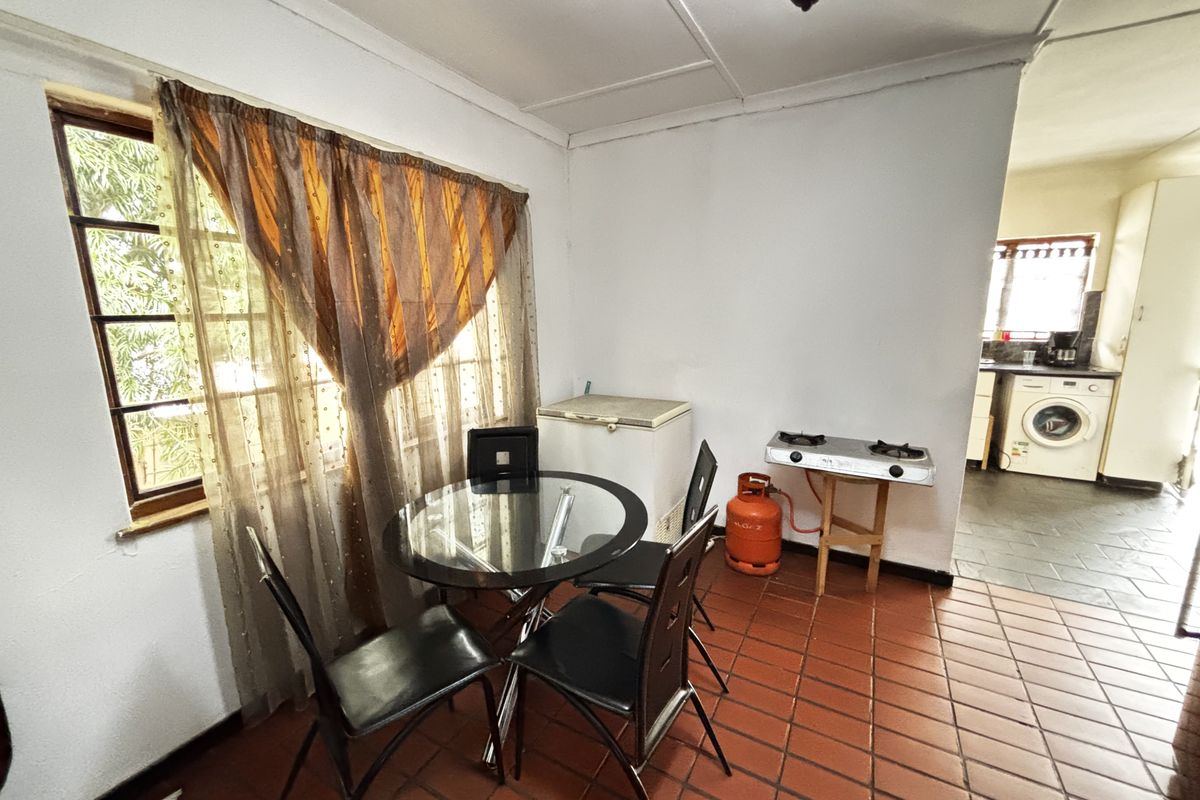 A functional kitchen area featuring terracotta floor tiles, a gas hob, and an adjacent utility space with laundry connections.