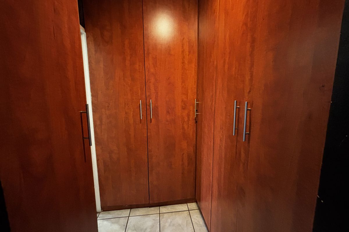 A bedroom area featuring extensive built-in wooden cabinetry and tiled flooring, providing ample storage space.