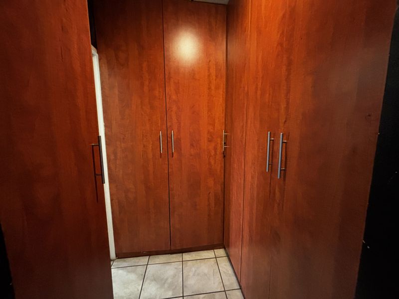 A bedroom area featuring extensive built-in wooden cabinetry and tiled flooring, providing ample storage space.