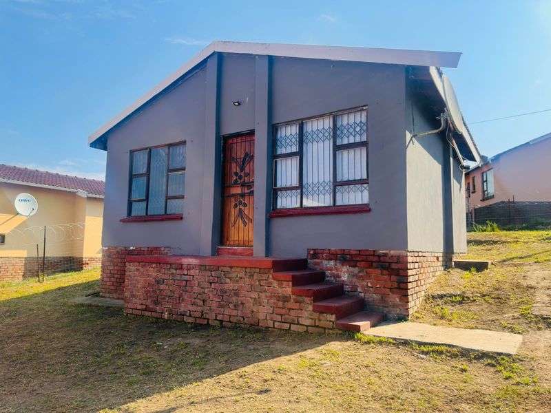 Front view of a detached house featuring a brick foundation, security gate, and security bars on the windows.
