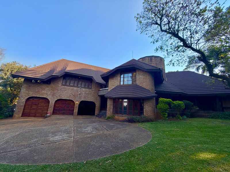 A distinctive multi-level brick residence featuring a prominent tiled roof, double garage, and a spacious concrete driveway set within a landscaped garden.