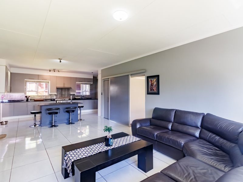 Spacious open-plan living area featuring a modern kitchen with a central island, sleek cabinetry, and tiled flooring throughout.
