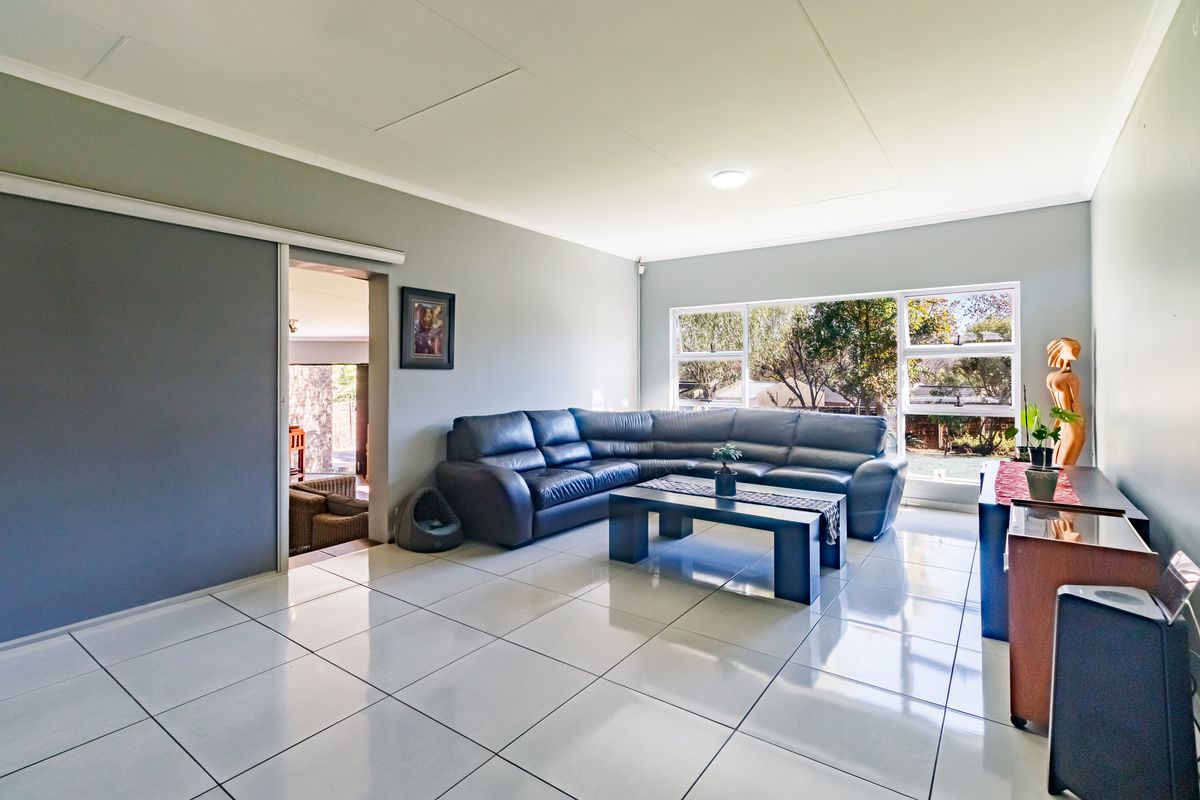 Spacious living room featuring large windows, neutral grey walls, and polished white tiled flooring, offering a bright and open atmosphere.