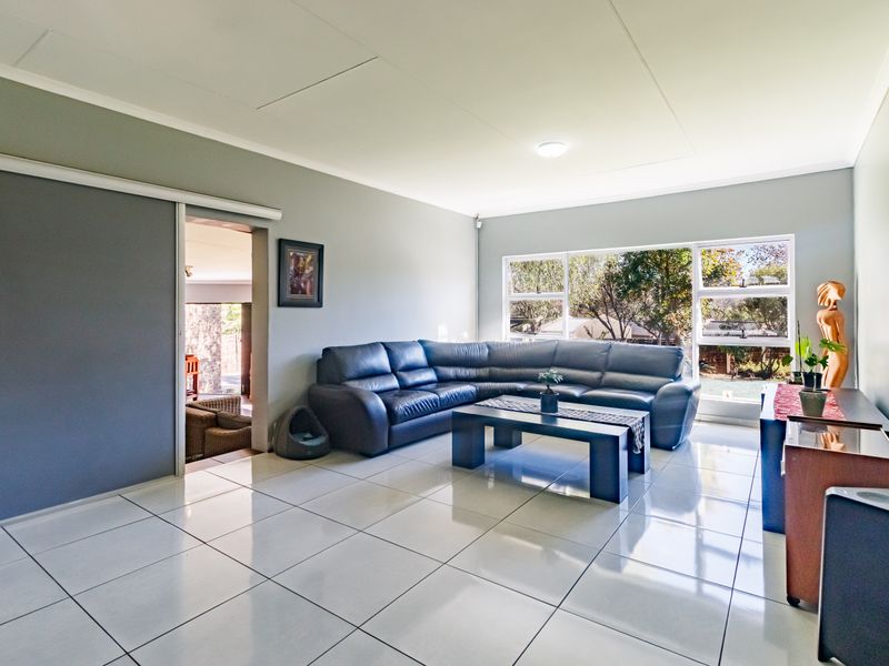 Spacious living room featuring large windows, neutral grey walls, and polished white tiled flooring, offering a bright and open atmosphere.