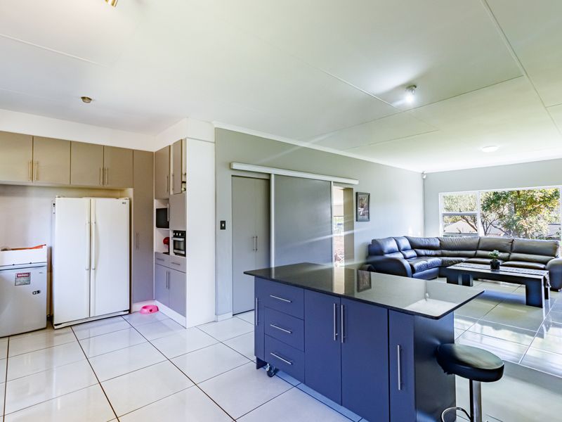 Spacious open-plan living area featuring a modern kitchen with a central island, granite countertops, built-in oven, and sleek tiled flooring throughout.