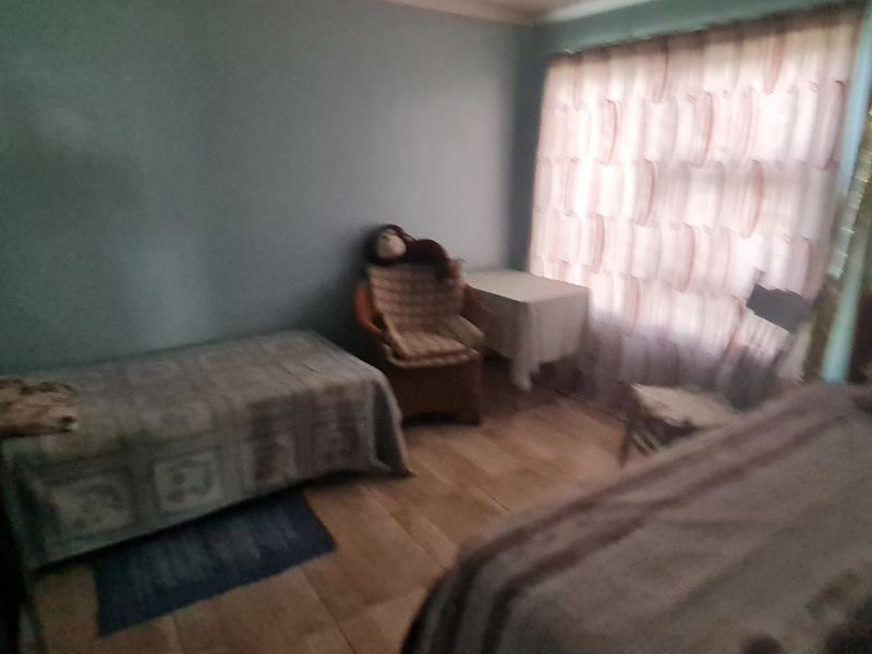 A bedroom featuring tiled flooring and standard ceiling cornicing, currently furnished with multiple beds.
