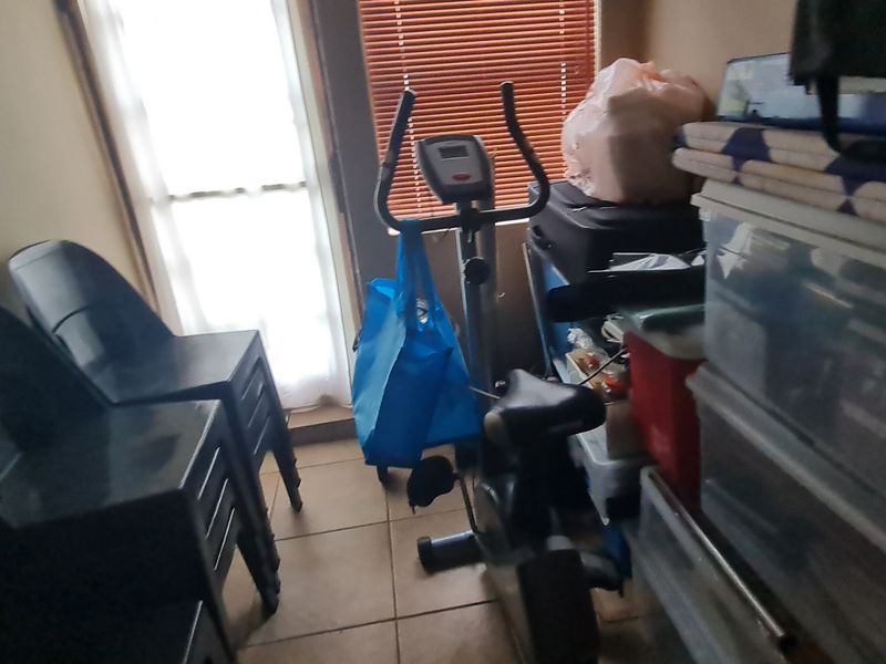 A cluttered utility space or small room featuring tiled flooring and a window with blinds, currently used for storage.