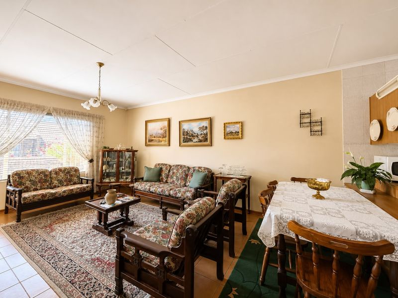 Spacious open-plan living and dining area featuring tiled flooring, neutral walls, and large windows providing ample natural light.