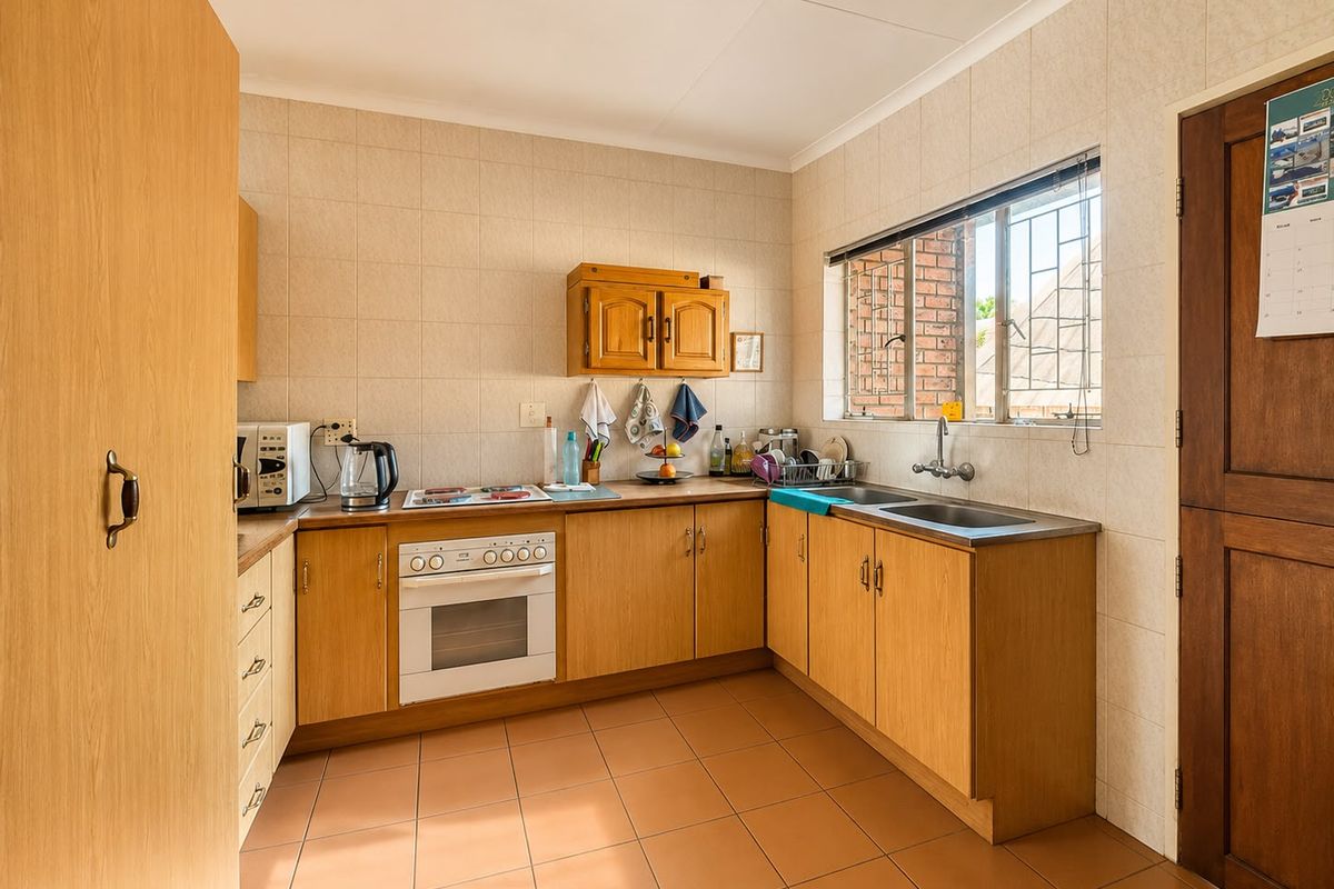 A functional kitchen featuring wooden cabinetry, laminate countertops, a built-in oven, and ceramic tiling throughout.