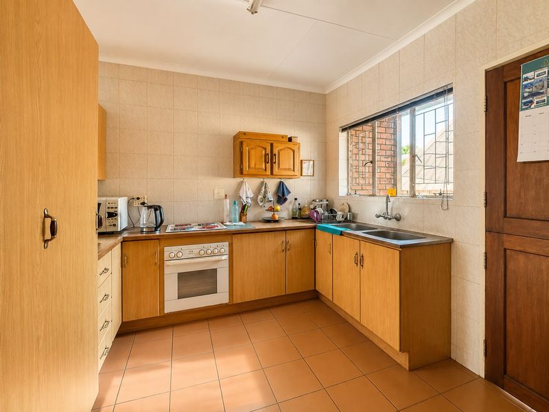 A functional kitchen featuring wooden cabinetry, laminate countertops, a built-in oven, and ceramic tiling throughout.