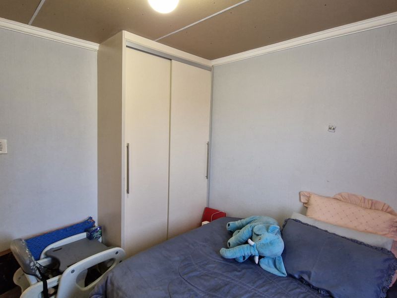 A bedroom featuring a built-in wardrobe and crown molding, currently requiring ceiling finishing and minor wall repairs.