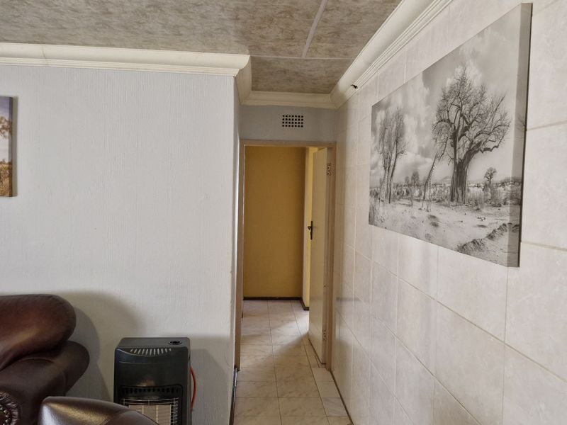 A functional hallway featuring tiled flooring and wall tiling, providing access to adjacent rooms within the home.