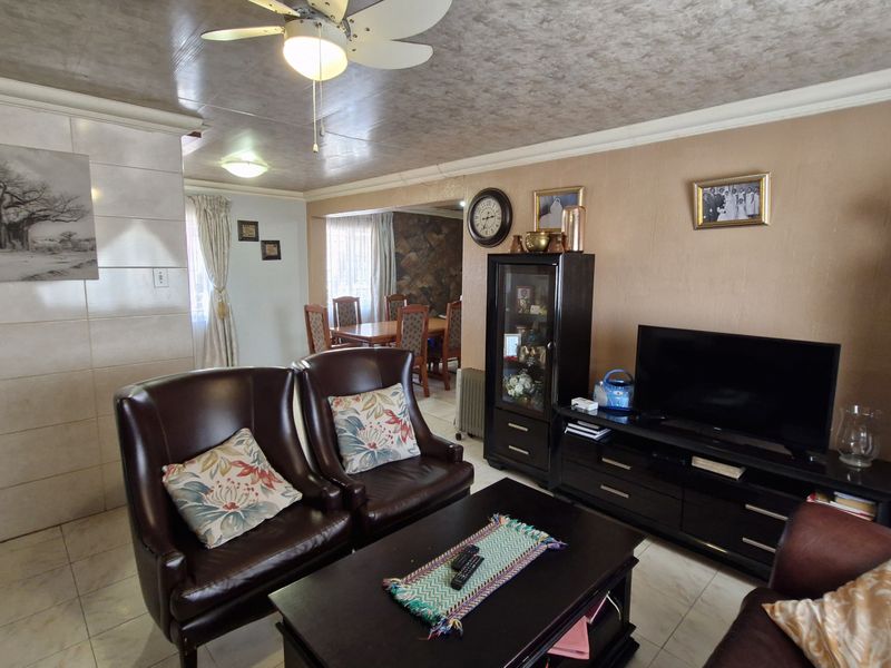 Open plan living and dining area featuring tiled flooring, a ceiling fan, and a stone accent wall in the dining space.