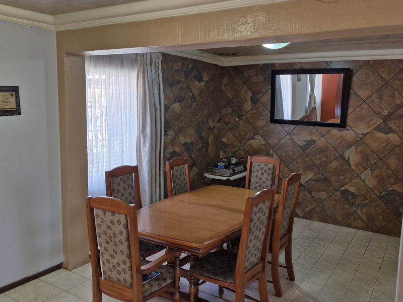 Dining area featuring tiled flooring and stone-look wall cladding, providing a functional space that could benefit from modern updates to the finishes.