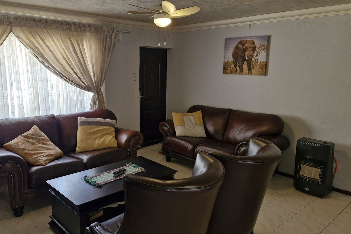A comfortable living room featuring tiled flooring, coved cornicing, and a ceiling fan, providing a functional and well-lit space for relaxation.