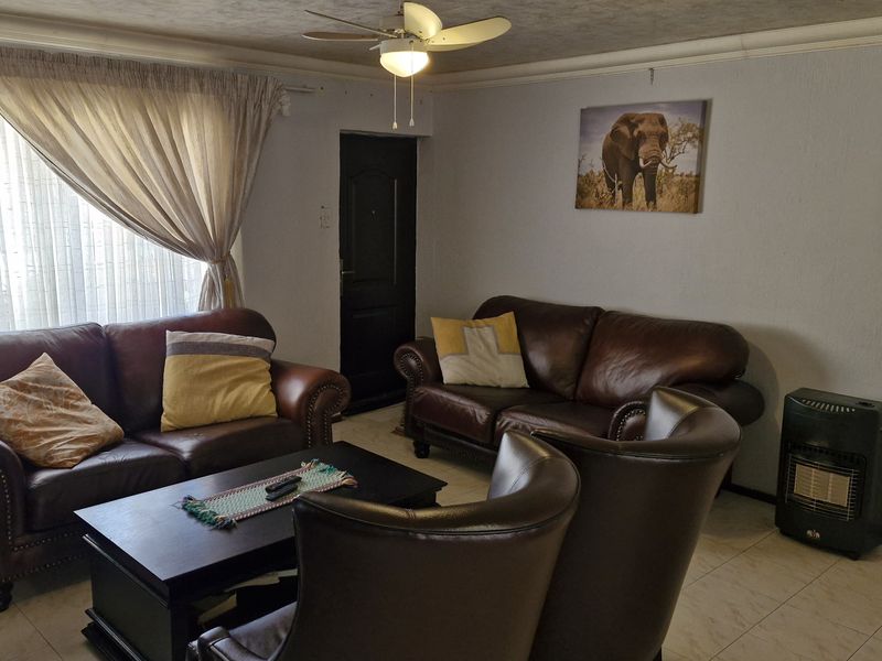 A comfortable living room featuring tiled flooring, coved cornicing, and a ceiling fan, providing a functional and well-lit space for relaxation.