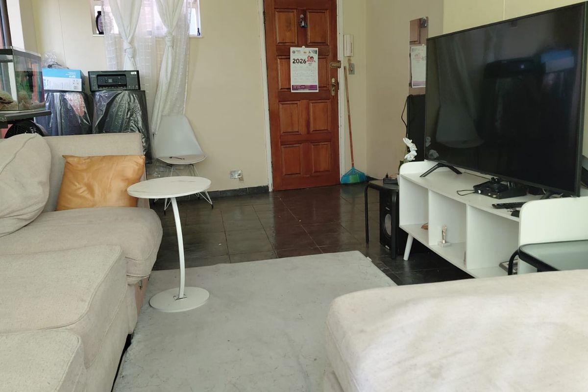 A living room area featuring tiled flooring and a timber entrance door, providing a functional space for relaxation.